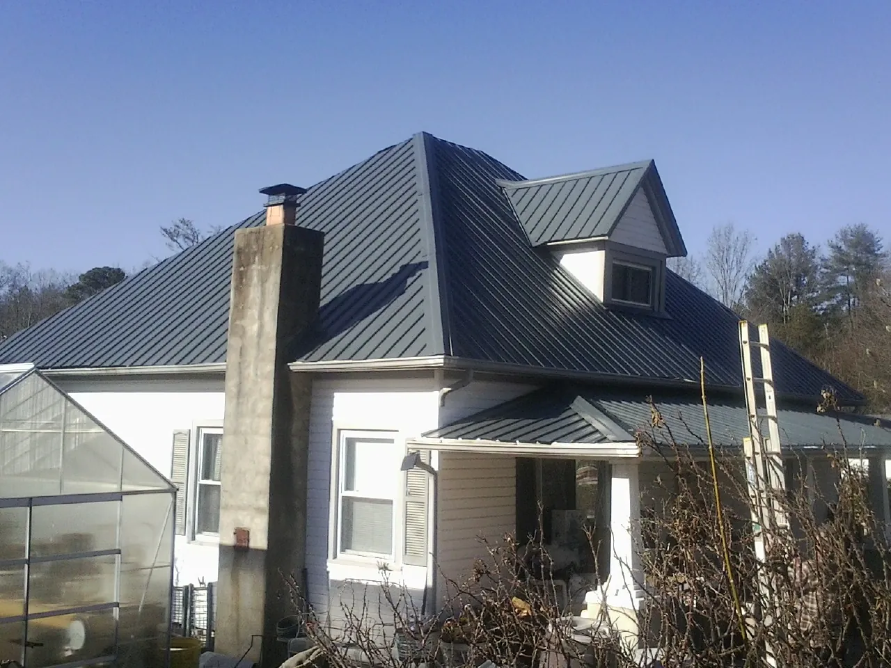 Dark blue standing seam metal roof on a white farmhouse with dormer — Slate & Tile Roof Repair by Roofing Brothers in Mc Henry