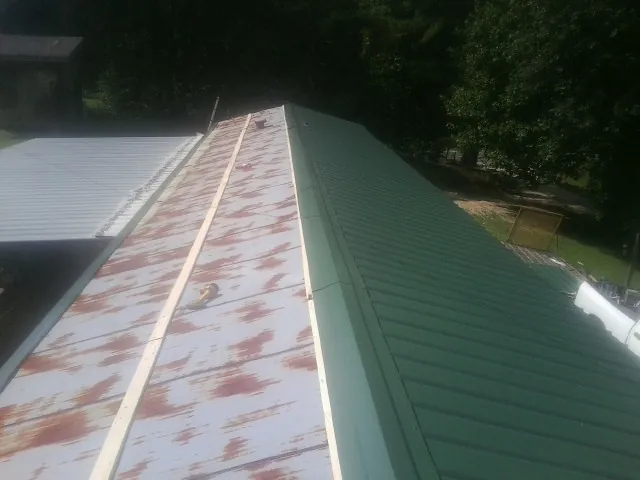 Old rusted panels beside newly installed green metal roofing — Wind Damage Roof Repair by Roofing Brothers in Mc Henry