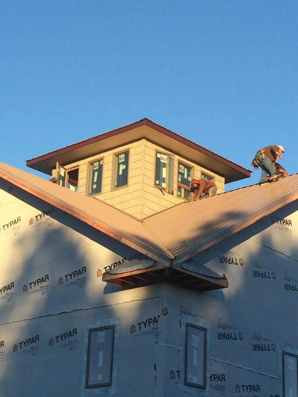 Roofers working around a rooftop cupola on a new metal roof at sunset — Roof Waterproofing in Mc Henry by Roofing Brothers